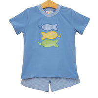 Children's blue shirt with fish appliqués and shorts on a hanger against a white background